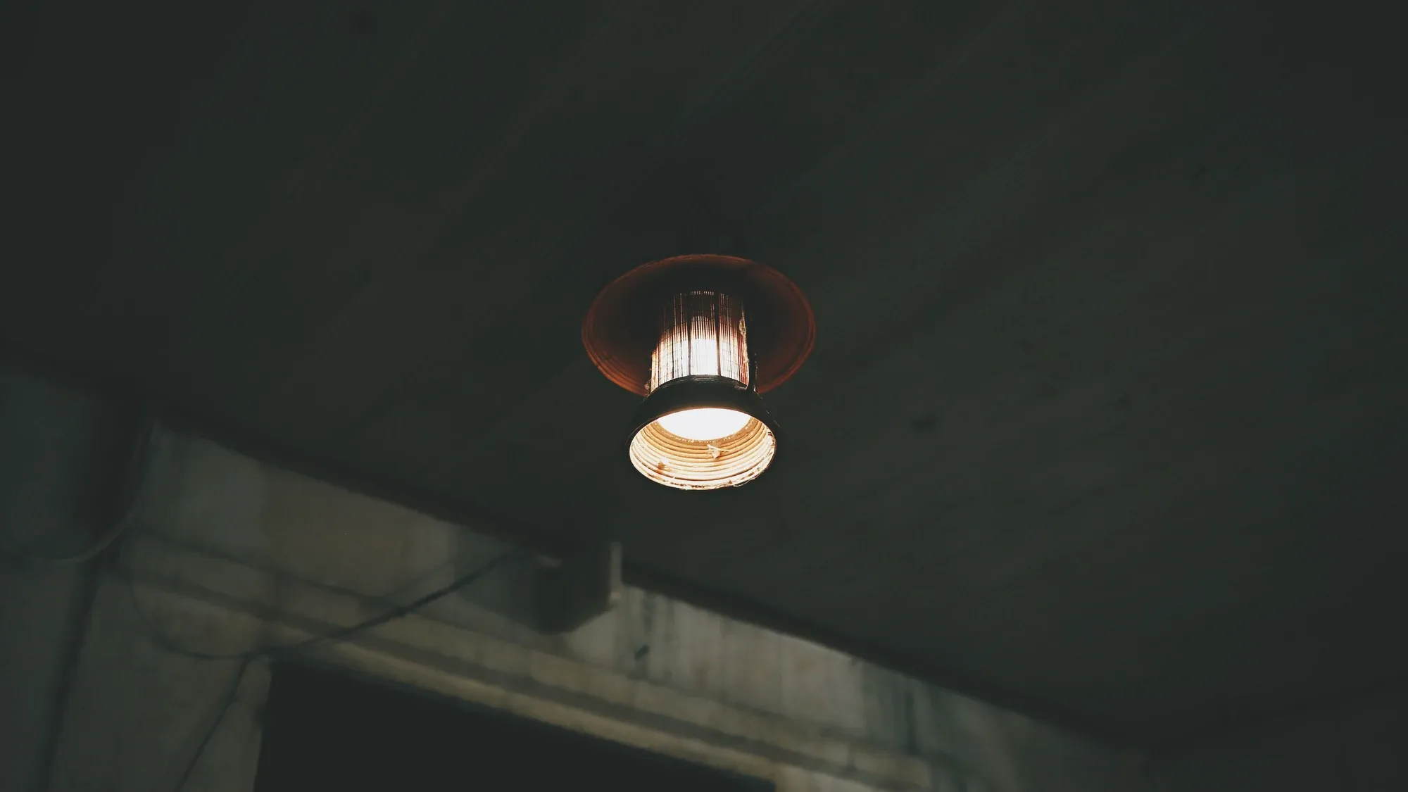 Deckenlampe in einem dunklen Raum, Blick auf Decke und Wand