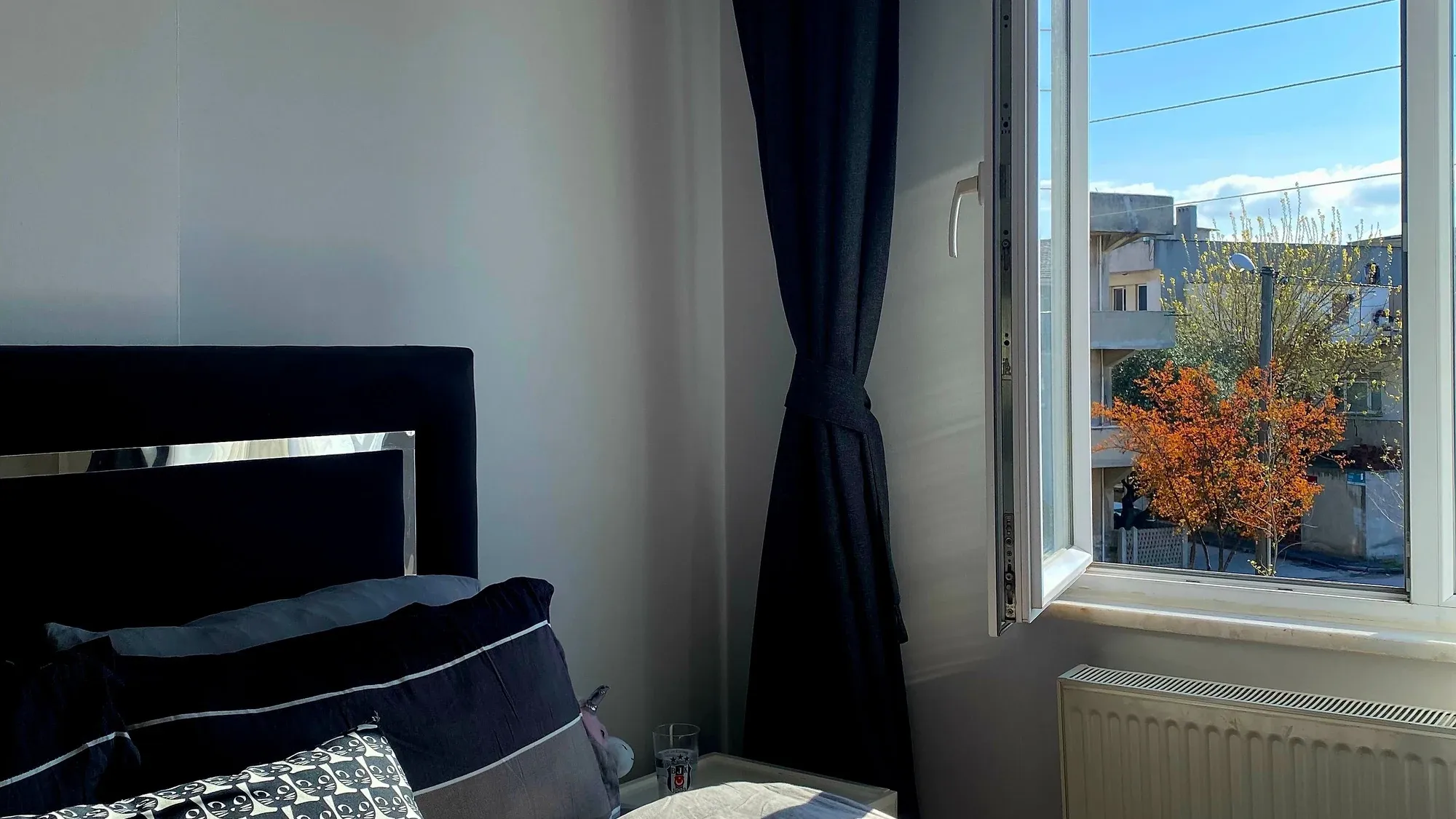Schlafzimmer mit geöffnetem Fenster, Vorhang bewegt sich