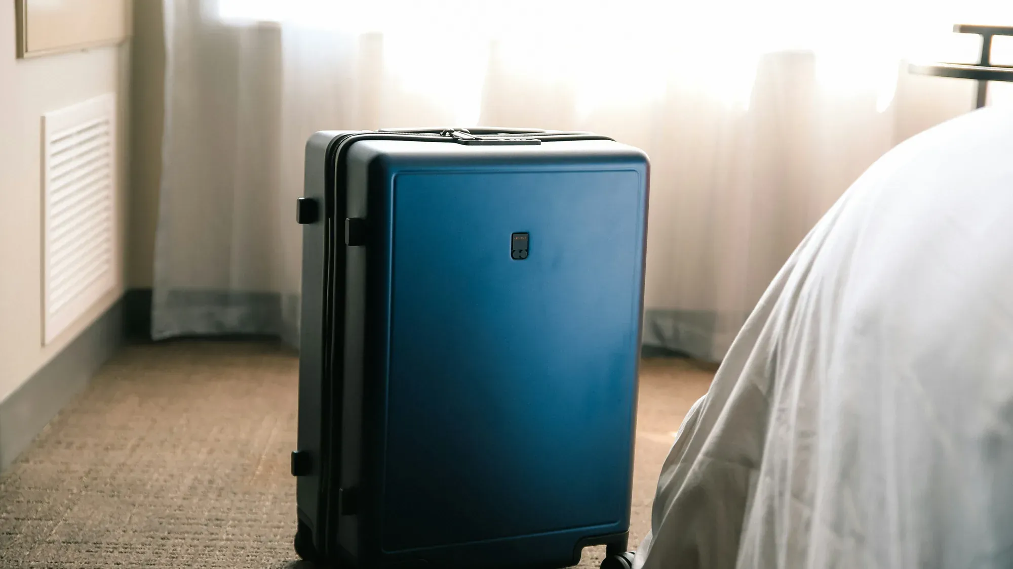 Koffer neben dem Bett im Hotelzimmer