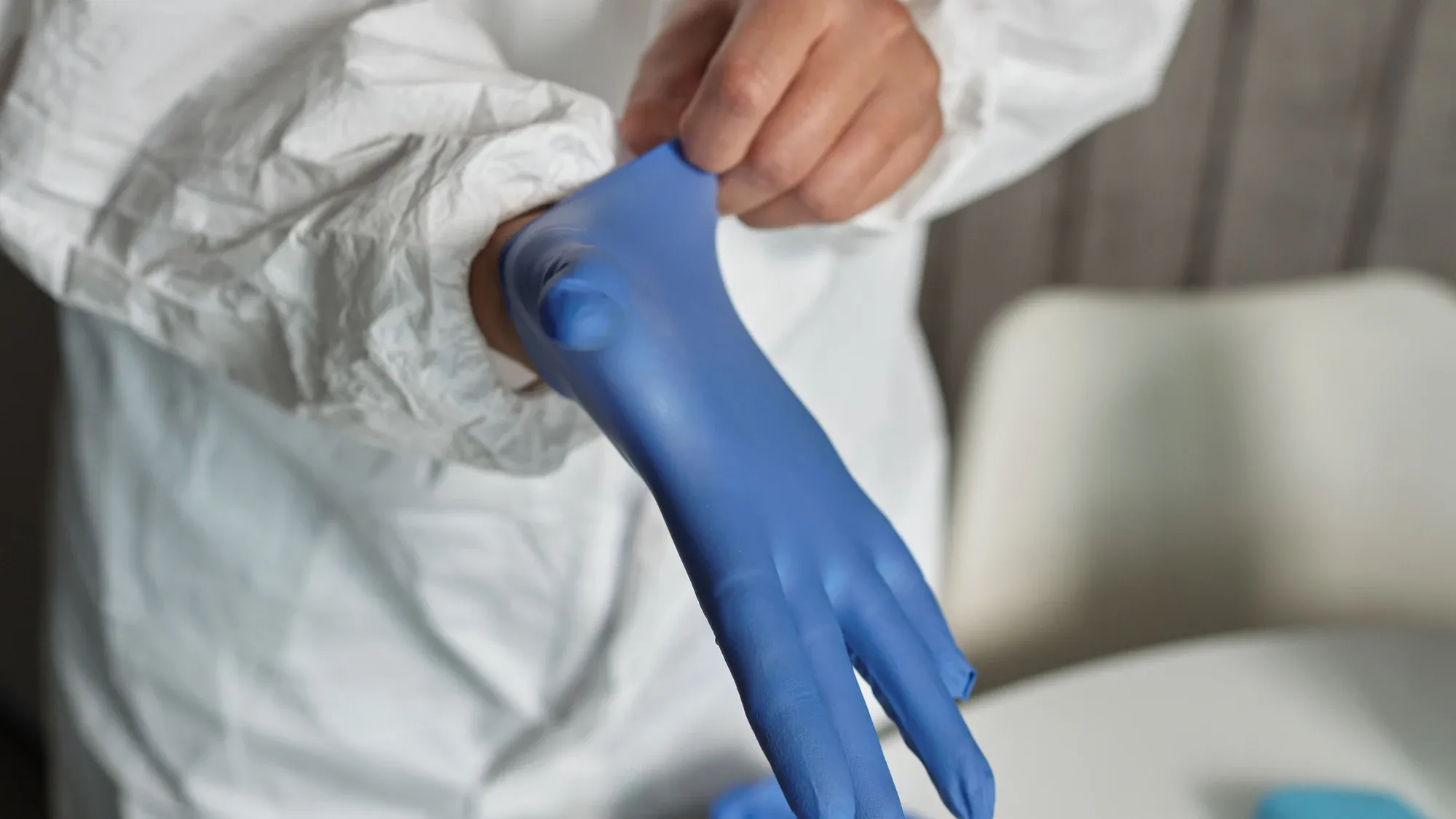 Fachkraft im Schutzanzug zieht Handschuhe an