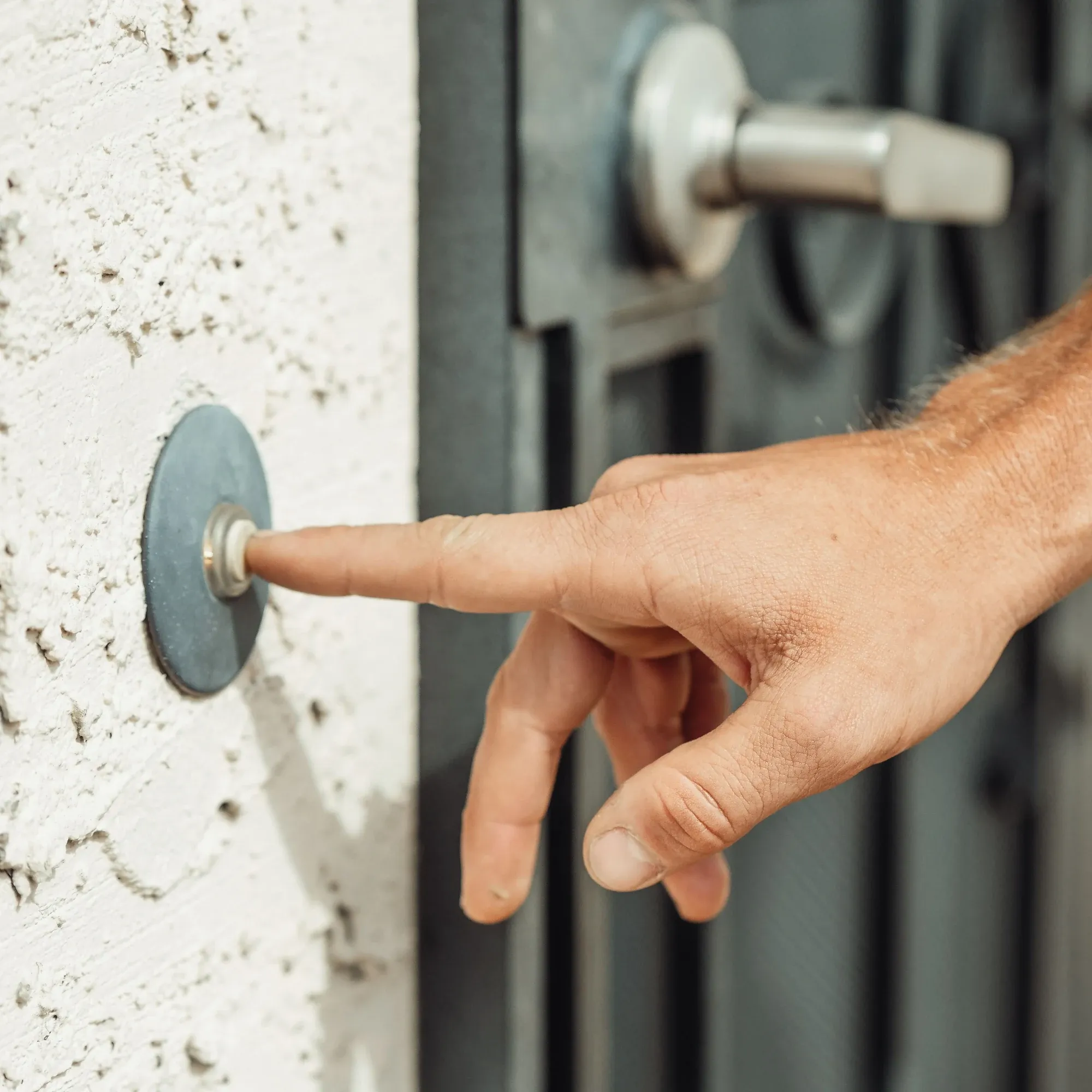 Finger drückt eine Türklingel neben der Haustür