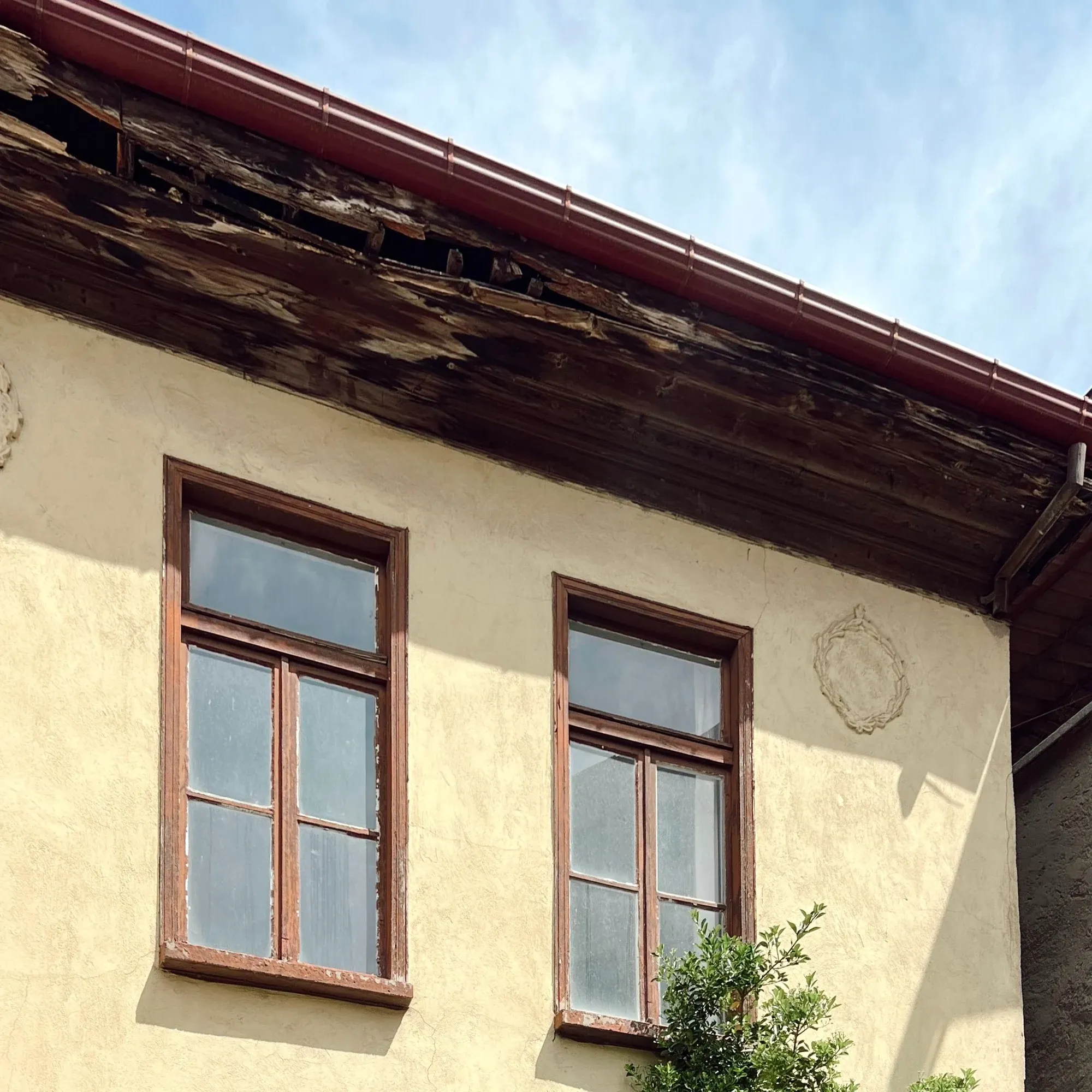 Fassade mit beschädigter Dachuntersicht und Fenstern