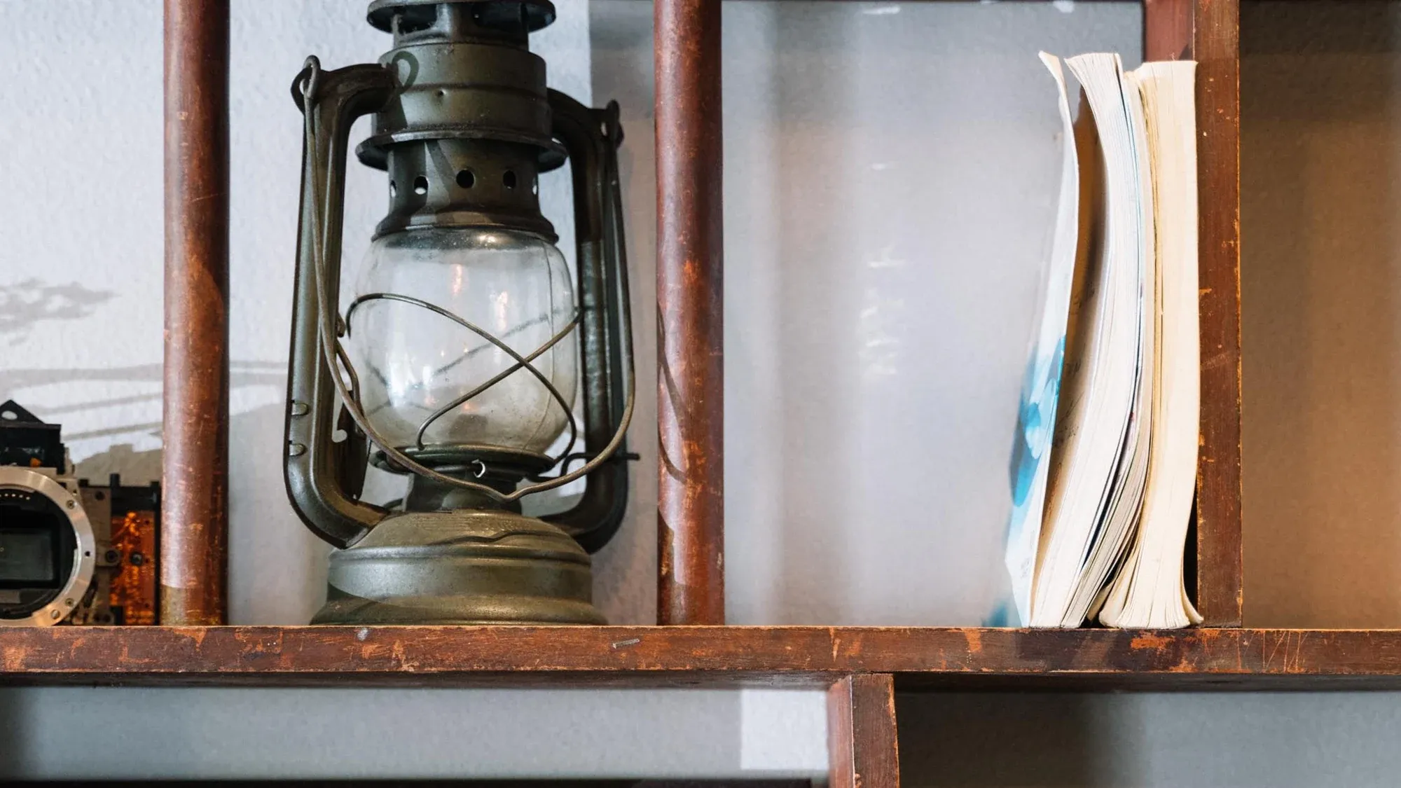 Altes Holzregal mit Petroleumlampe und Büchern